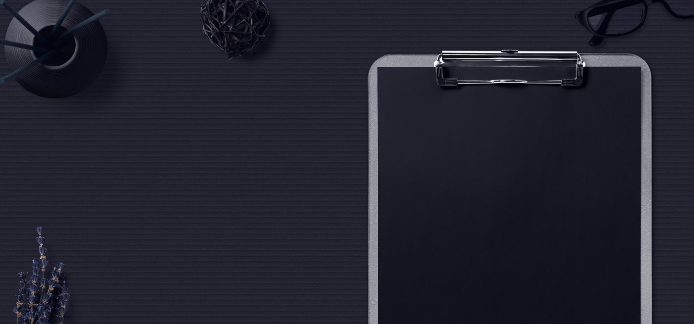 Clipboard und Schreibtischutensilien auf schwarzem Hintergrund.